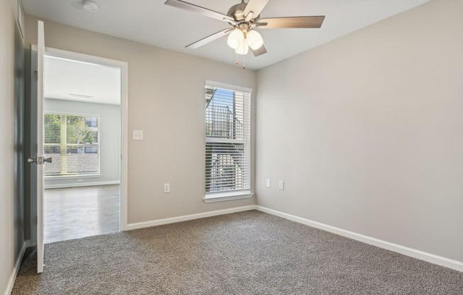 an empty living room with a ceiling fan and a window