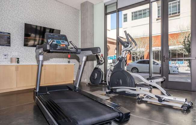 A treadmill and a stationary bike are in a gym.
