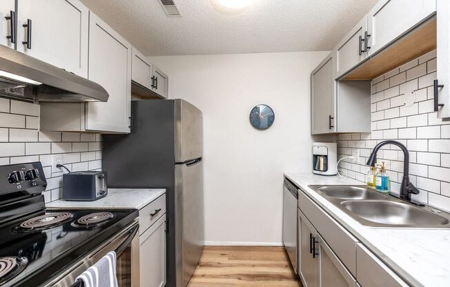 an empty kitchen with stainless steel appliances and white cabinets