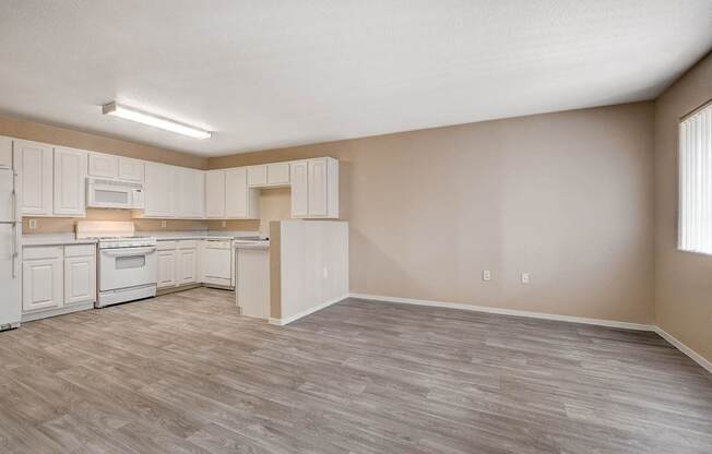 A kitchen with white cabinets and a wooden floor.