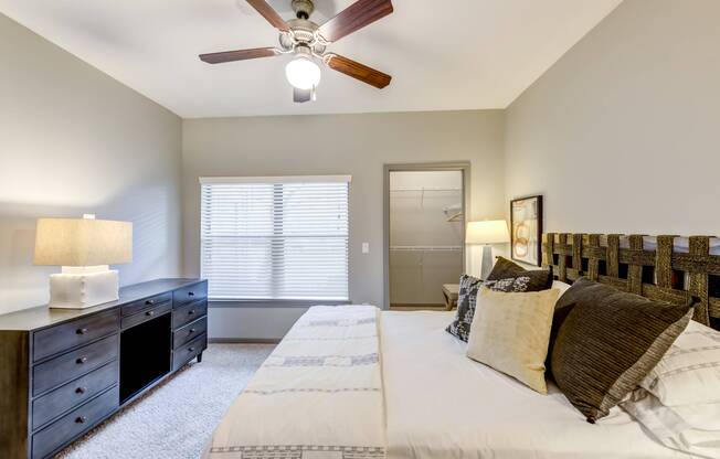 Spacious bedroom with large window, walk-in closet, and ceiling fan at Avenues at Craig Ranch apartments for rent