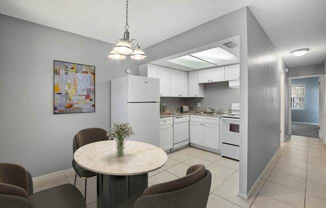 A kitchen with a table and chairs in the foreground and a refrigerator in the background.