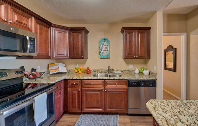 a kitchen with wooden cabinets and stainless steel appliances at Villas on Bell, Phoenix, 85053