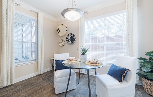 A dining area with a table, chairs, and a potted plant.