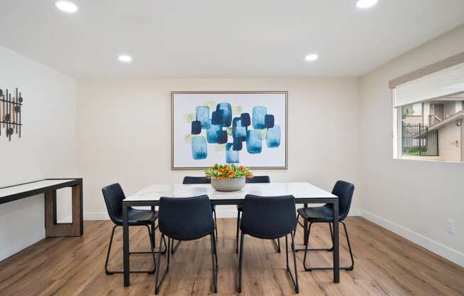 a dining room with a table and chairs and a painting on the wall