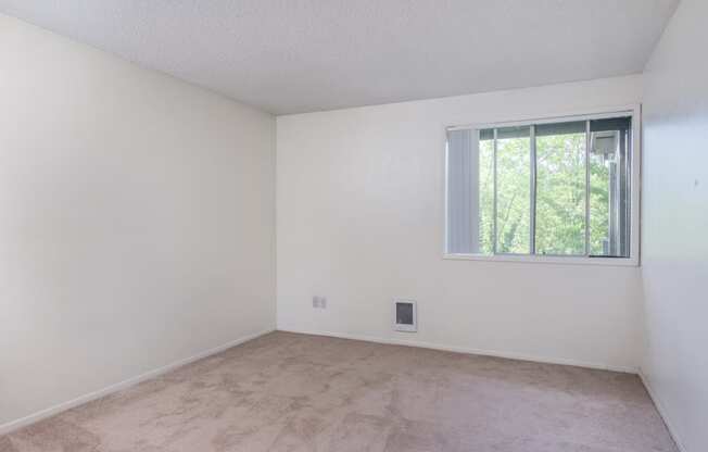 the living room of an empty apartment with a window