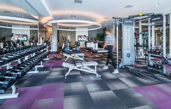 A gym with a variety of equipment including treadmills, weights, and exercise machines.