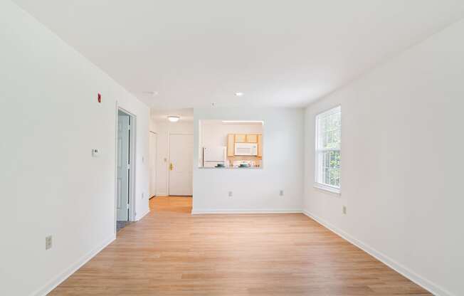 A white room with a wooden floor and a window.