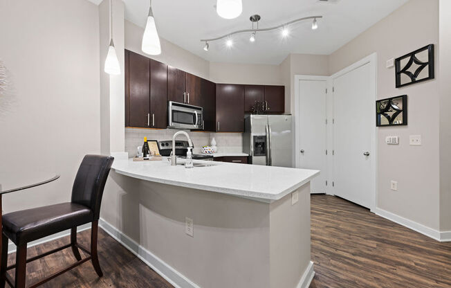 a white kitchen with a large island and black chairs