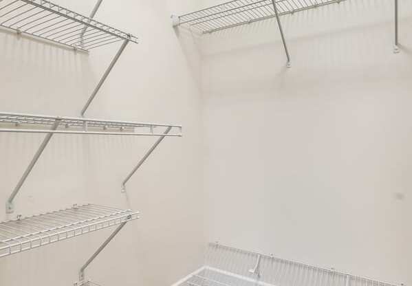 an empty closet with empty shelves in a room with carpet and white walls