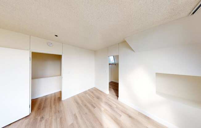 a bedroom with white walls and hardwood floors