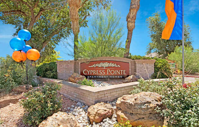 A welcoming community entrance sign here at Cypress Pointe with a brick monument, clear property signage, and landscaped surroundings creating a strong first impression. Mature trees, desert-style landscaping, and colorful accents add curb appeal and highlight the inviting atmosphere of the apartment community.