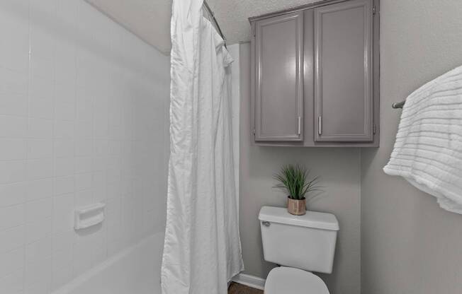 A white toilet sits in a bathroom next to a white shower curtain.