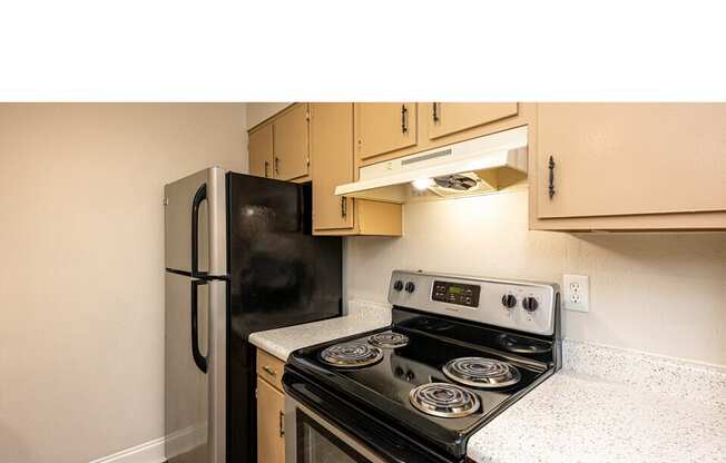 A black stove and refrigerator in a kitchen.