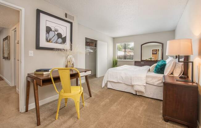 a bedroom with a bed and a desk with a yellow chair at Lodge of Overland Park Apartments, Overland Park , Kansas