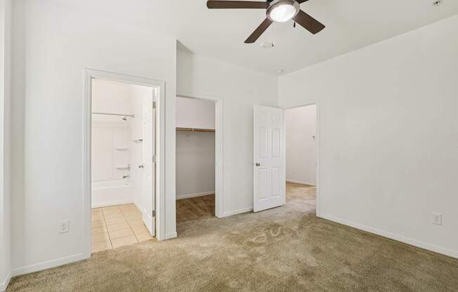 A room with a ceiling fan and carpeted floor.