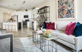 A modern living room with a white couch and a large painting on the wall.