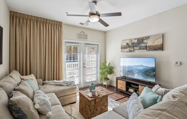 A living room with a grey couch and a flat screen TV.at Century Hampton Roads, Suffolk Virginia  