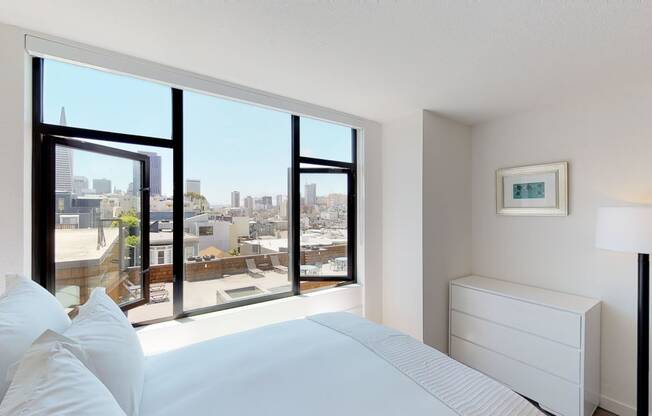 a bedroom with a large window and a white bed