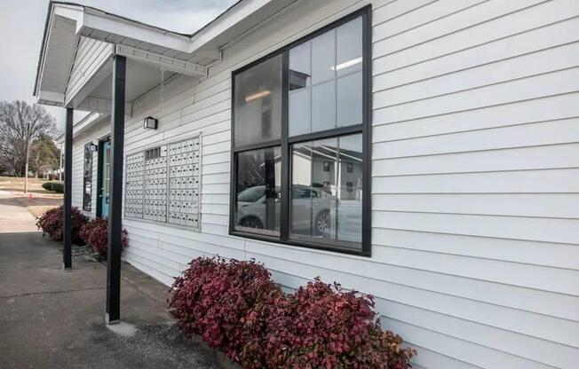 the side of a white building with windows and a sidewalk at Cleo Apartments, Athens, AL