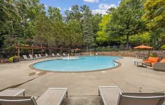 a swimming pool with chairs and trees in the background