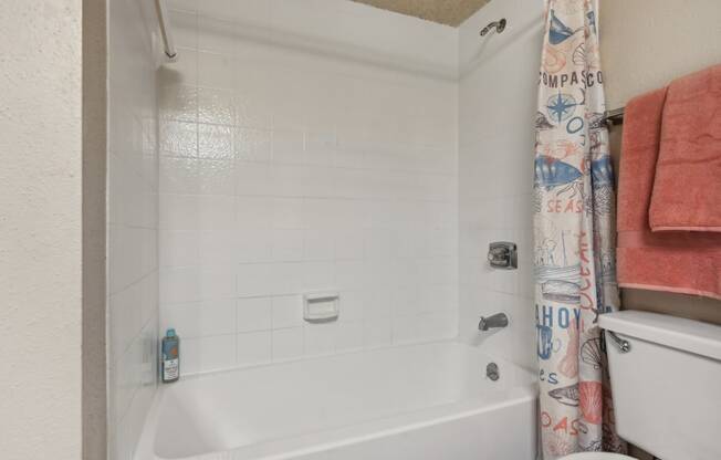 a bathroom with a tub and a toilet and a shower curtain