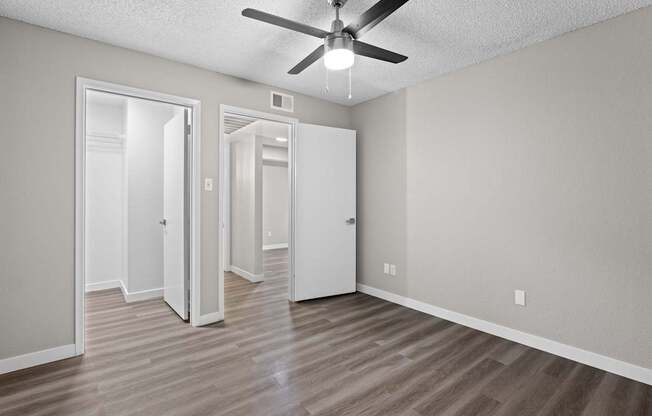 A room with a ceiling fan and three doors.