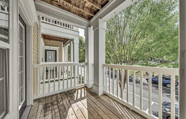 a covered porch with wood floors and white railings