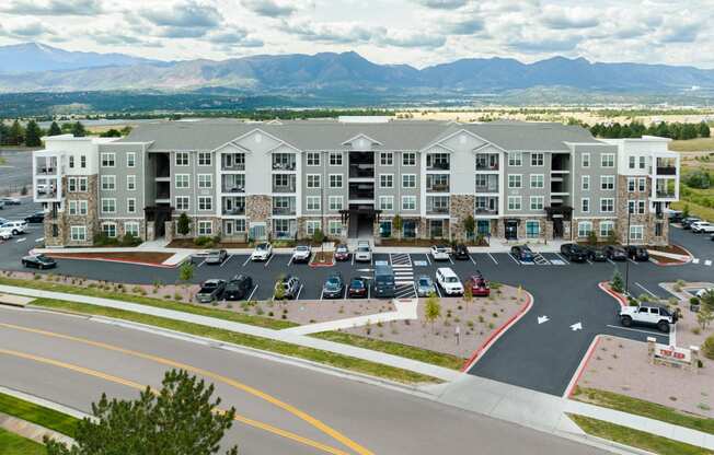 an aerial view of an apartment complex with a parking lot and mountains in the background