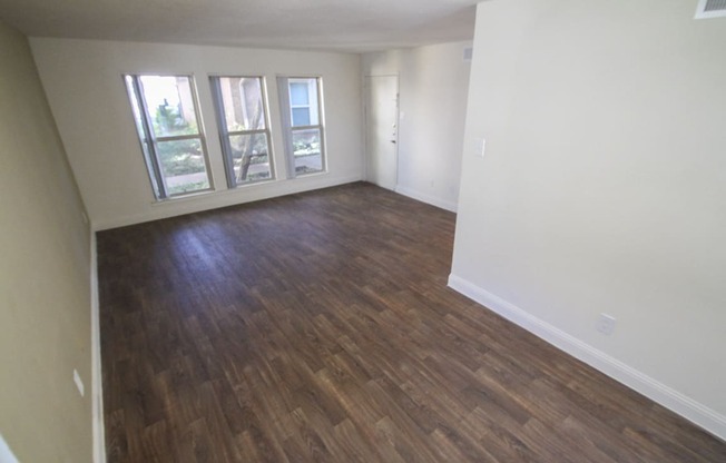 This is a photo of the living room with hardwood vinyl flooring in the 751 square foot 1 bedroom apartment at Woodbridge Apartments in Dallas, TX.