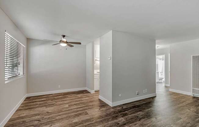 A spacious room with wood flooring and a ceiling fan.
