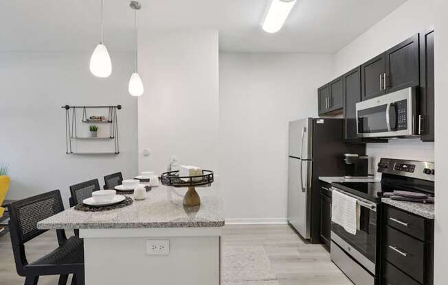 A kitchen with black cabinets and a granite countertop.