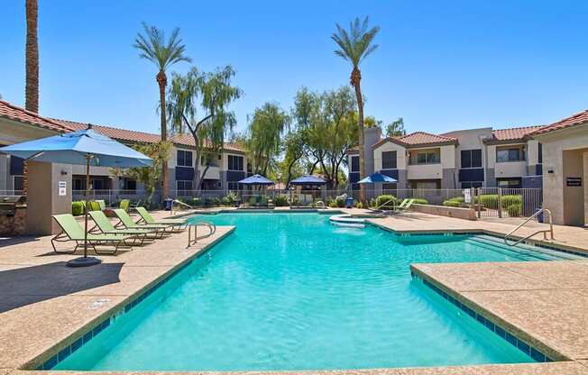 A large swimming pool surrounded by sun loungers and umbrellas.