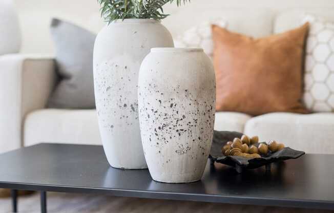a coffee table with two white vases and a plant on it