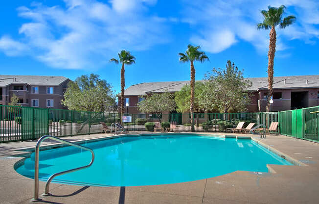 A swimming pool surrounded by palm trees and apartment buildings.