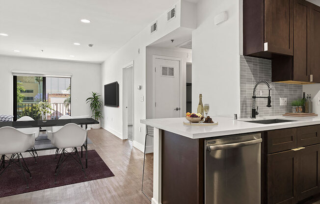 Tiled kitchen with stainless steel appliances and view of hardwood floored living room and balcony.