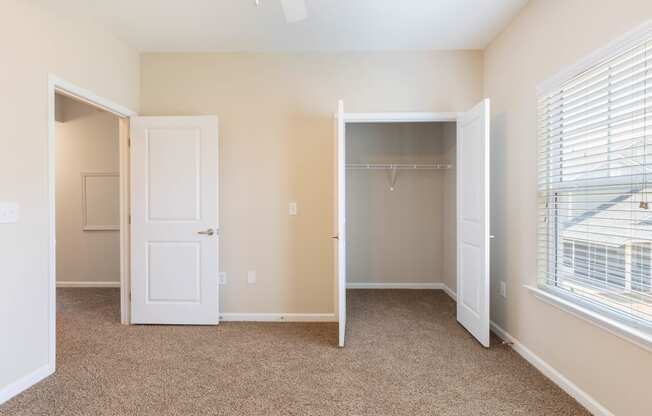 an empty bedroom with a closet and a window