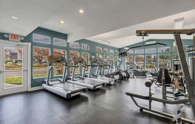 a gym with cardio equipment and windows with a view of the street at Misty Ridge Apartments, Virginia