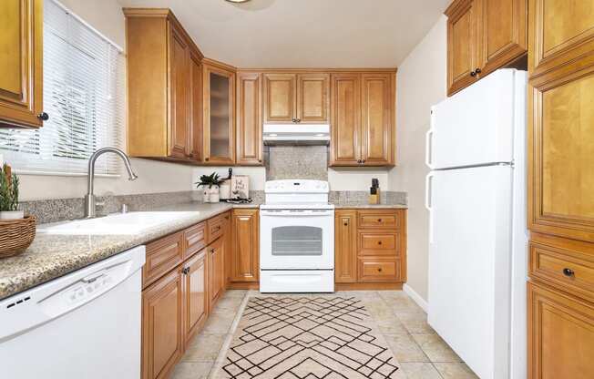Large U-shaped kitchen with granite countertops, dishwasher, sink, stove, oven and fridge at Pacific Sands, San Diego, California