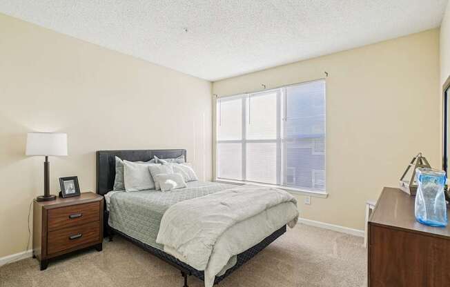 A bedroom with a bed, nightstand, and window.