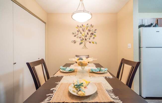 A dining table set for a meal with a decorative leaf hanging from the ceiling at Sterling Point Apartment Homes, Arizona, 85042