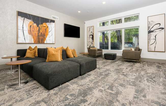 seating area with grey couch and tables with chairs by a window