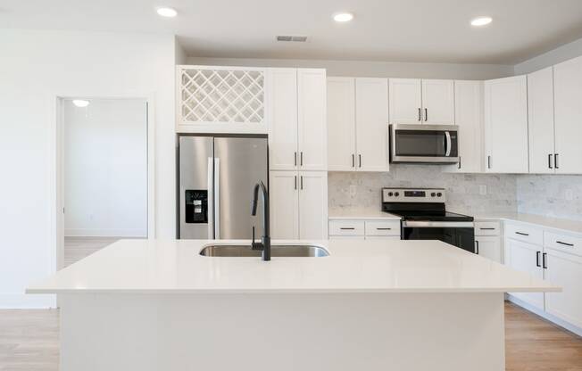 a large white kitchen with stainless steel appliances and white cabinets