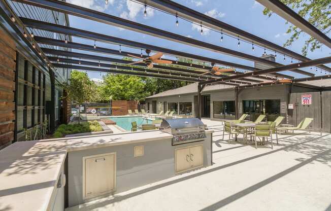 a patio with a grill and a pool in the background