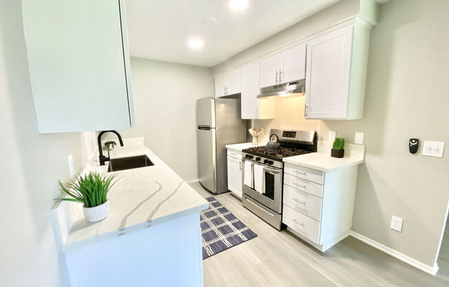 a kitchen with white cabinets and stainless steel appliances at BLVD Apartments LLC, Tarzana, 91356