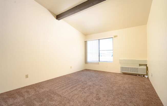 a bedroom with carpeted floors and a large window at Park Columbia Apts, California, 92544