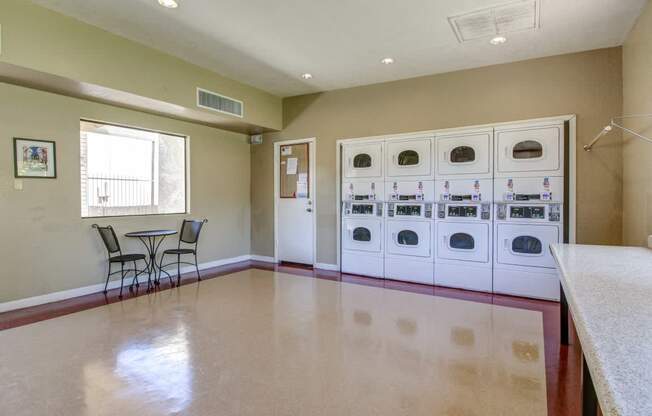 A kitchen with a table and chairs in the foreground and a laundry room in the background.