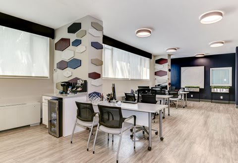 A room with a desk, chairs, and a large window with a view of the sky.