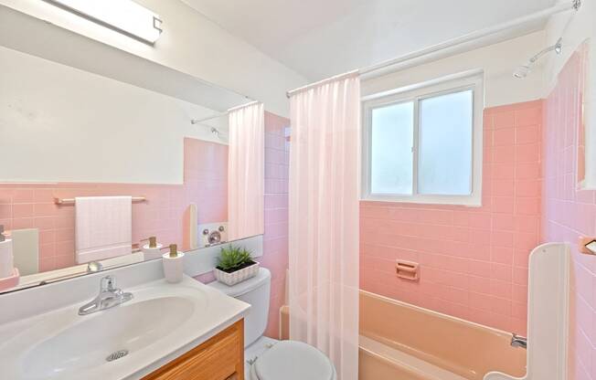 a bathroom with pink tiles and a sink and a toilet