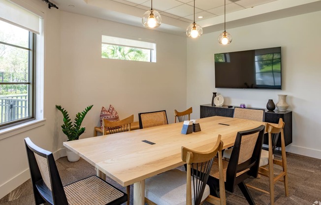 a conference room with a large wooden table and chairs and a flat screen tv on the wall